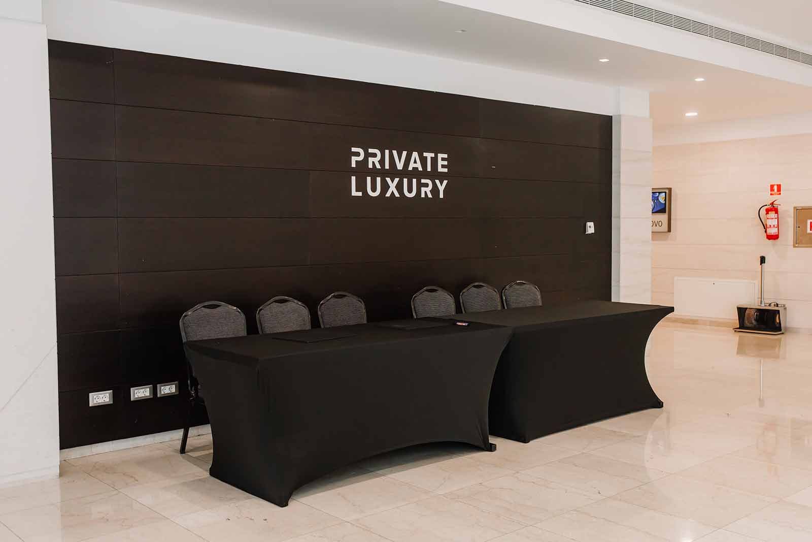 Registration desk in front of a dark wall with white 3D "Private Luxury" lettering